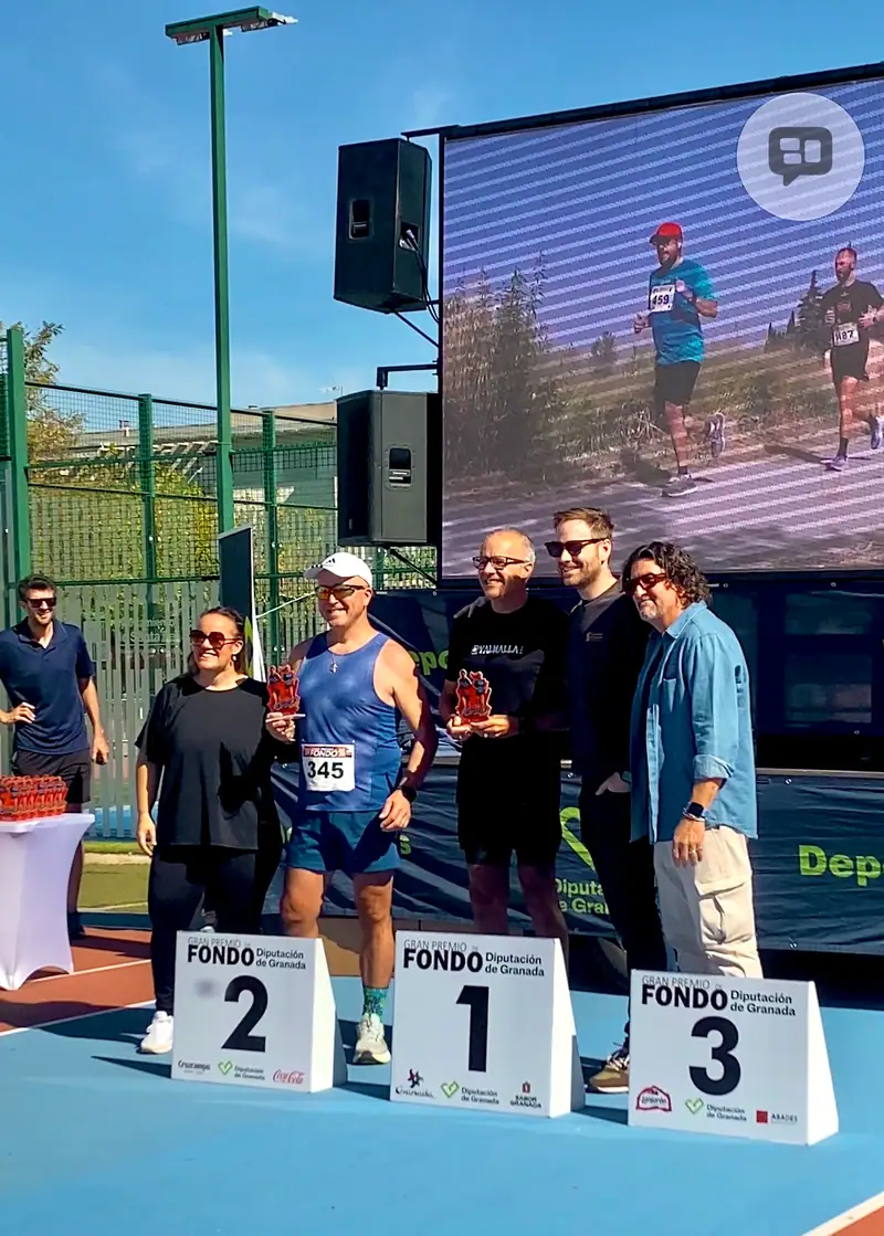 Uve con su trofeo sobre el primer escalón del podio, junto a otros participantes y acompañantes